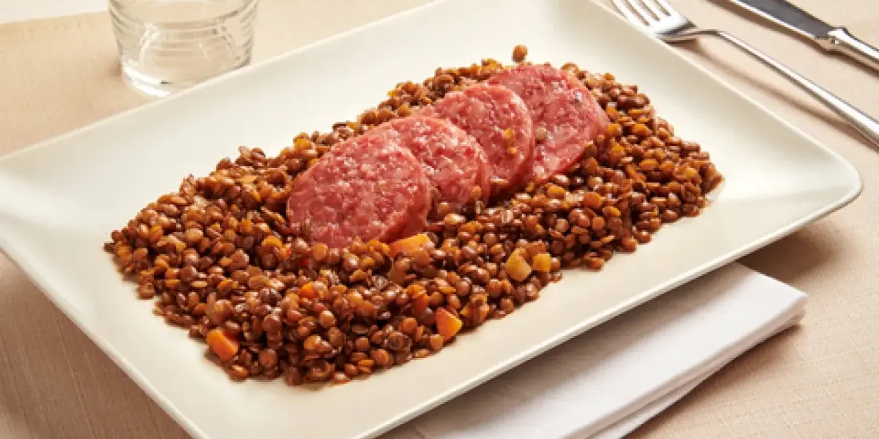 Piatto di lenticchie con fette di cotechino, un classico della tradizione.