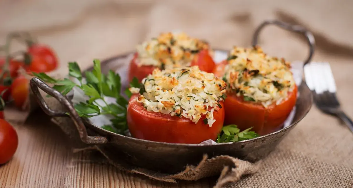 Pomodori ripieni di riso freddi, un piatto estivo gustoso e leggero, serviti in un vassoio rustico con prezzemolo fresco.