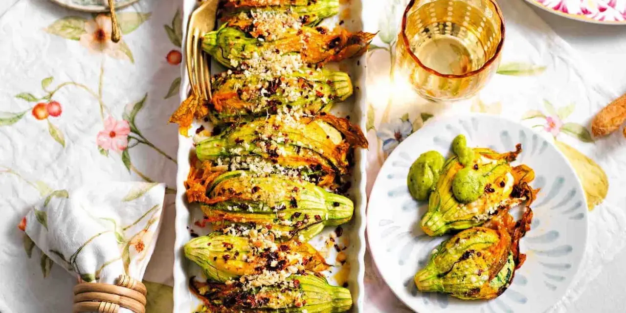 Deliziosi fiori di zucca ripieni, dorati e croccanti, serviti su un piatto con un tocco di verde.