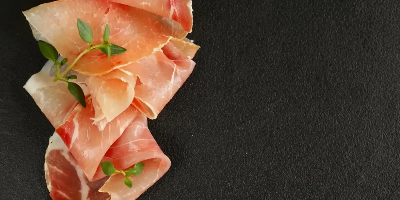 Fettine di prosciutto crudo e speck, con rametti di timo, per mostrare la differenza tra speck e prosciutto crudo.