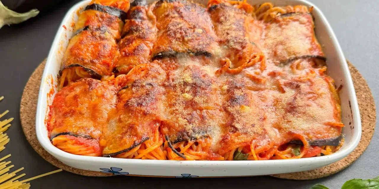 Involtini di melanzane ripieni di spaghetti al sugo, gratinati al forno con formaggio fuso.