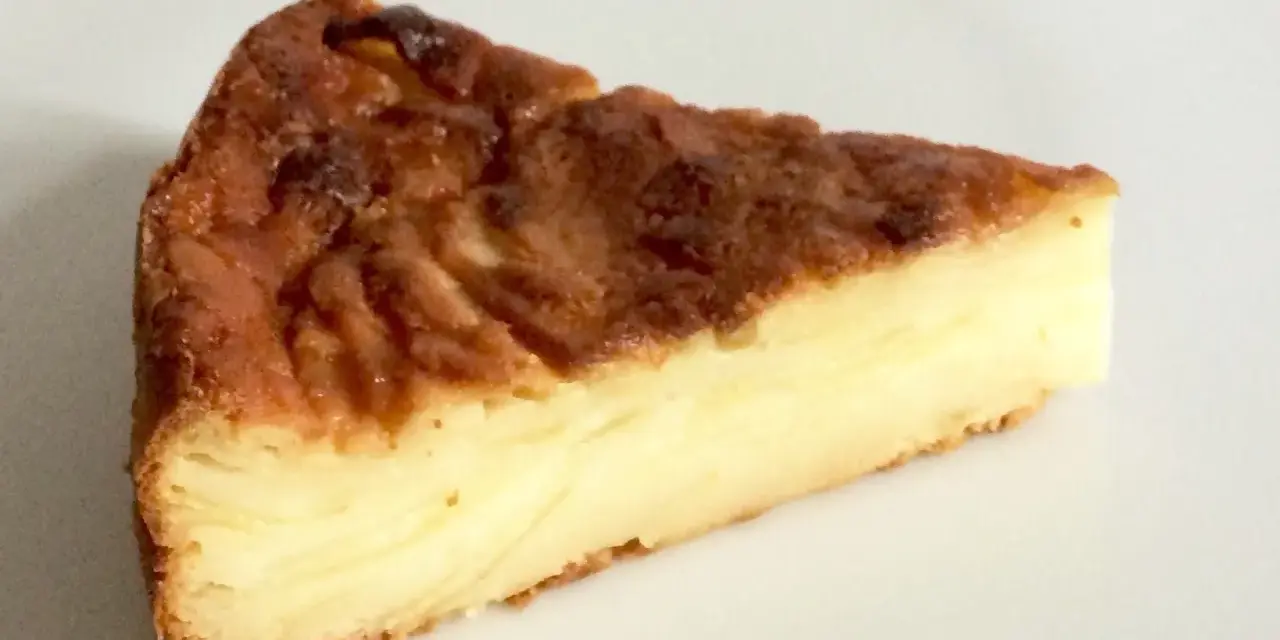 Una fetta di torta di mele fondente, con strati dorati e un ripieno cremoso.