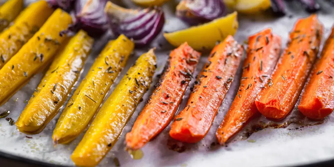 Carote, cipolle rosse e patate dorate, un tripudio di verdure al forno, condite con erbe aromatiche e olio.