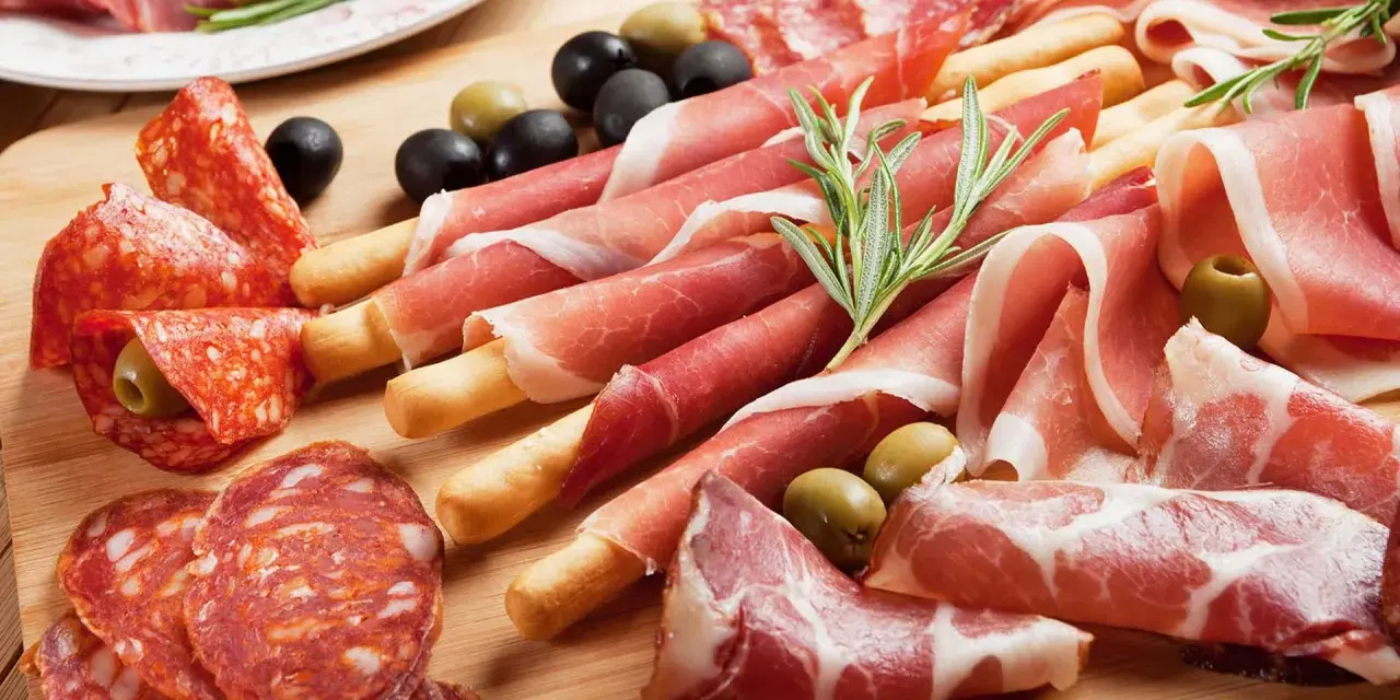 Tagliere con salumi misti, tra cui affettati non di maiale, olive e rosmarino.
