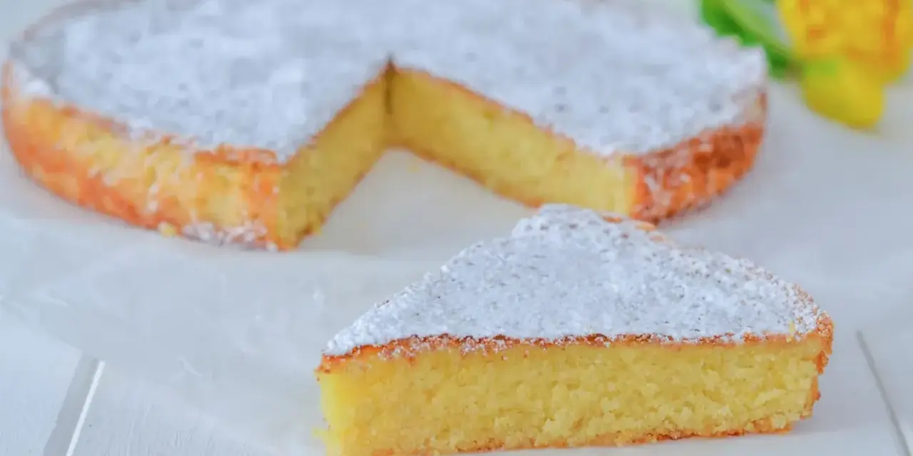 Una deliziosa torta caprese senza mandorle, spolverata di zucchero a velo, con una fetta tagliata.