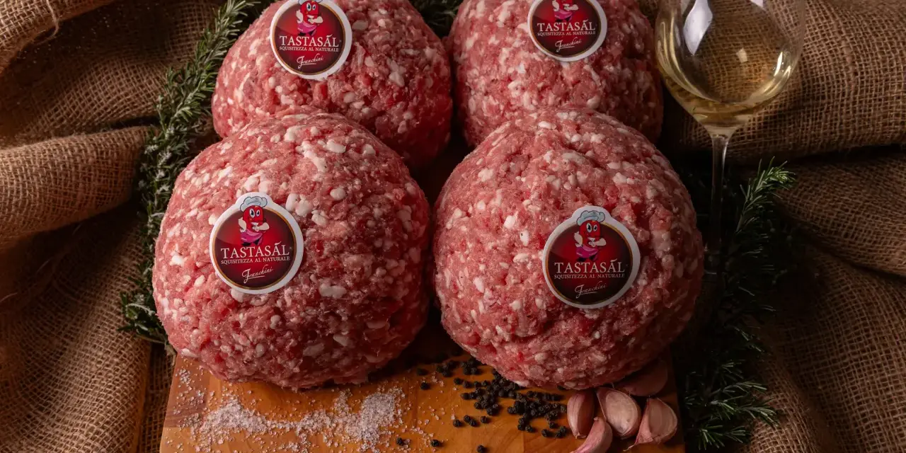 Quattro sfere di carne macinata TASTASAL, con rosmarino, aglio, pepe e sale su un tagliere. Ingredienti freschi per un sapore autentico.