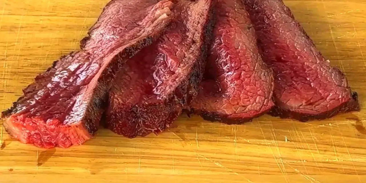 Fette succulente di spinacino di manzo, cotte alla perfezione, adagiate su un tagliere di legno.
