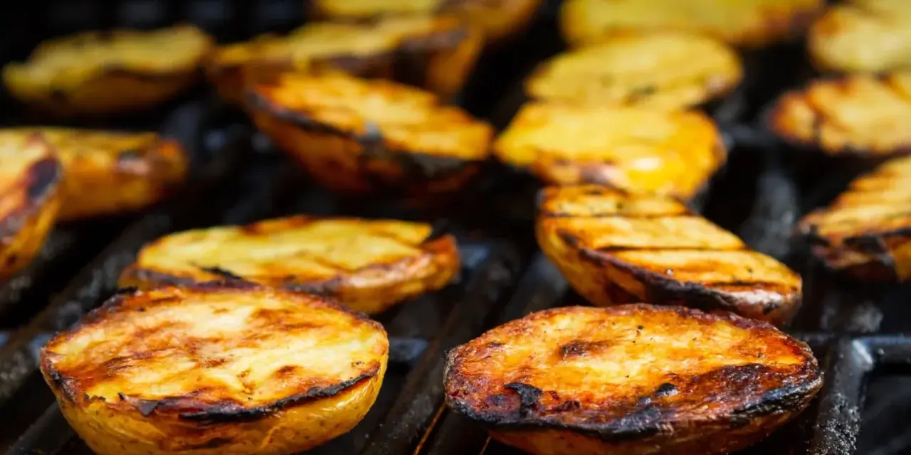 Patate alla brace dorate e succulente, con segni di grigliatura perfetti, pronte per essere gustate.