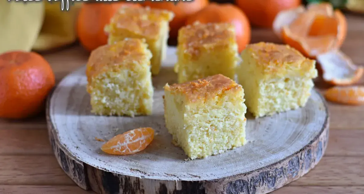 Fette di torta di clementine soffice, guarnite con scorza d'arancia, su un tagliere di legno.