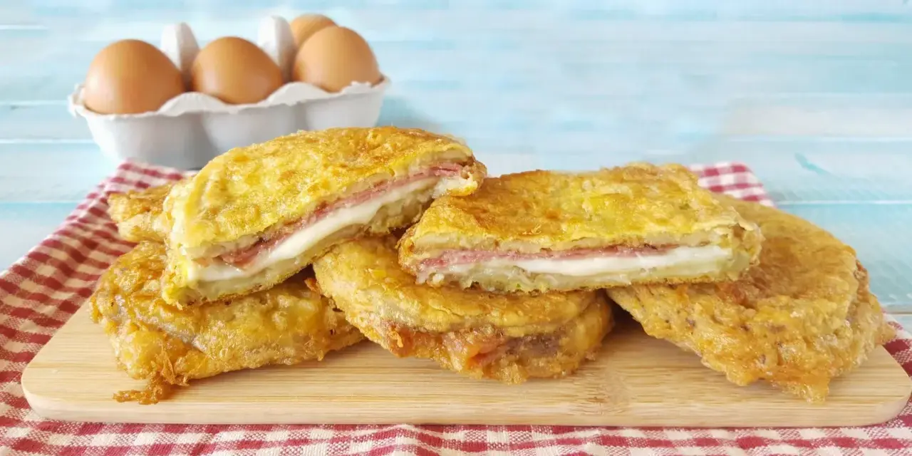 Fette dorate di melanzane alla pullastiello, ripiene di formaggio filante e salumi, pronte per essere gustate.