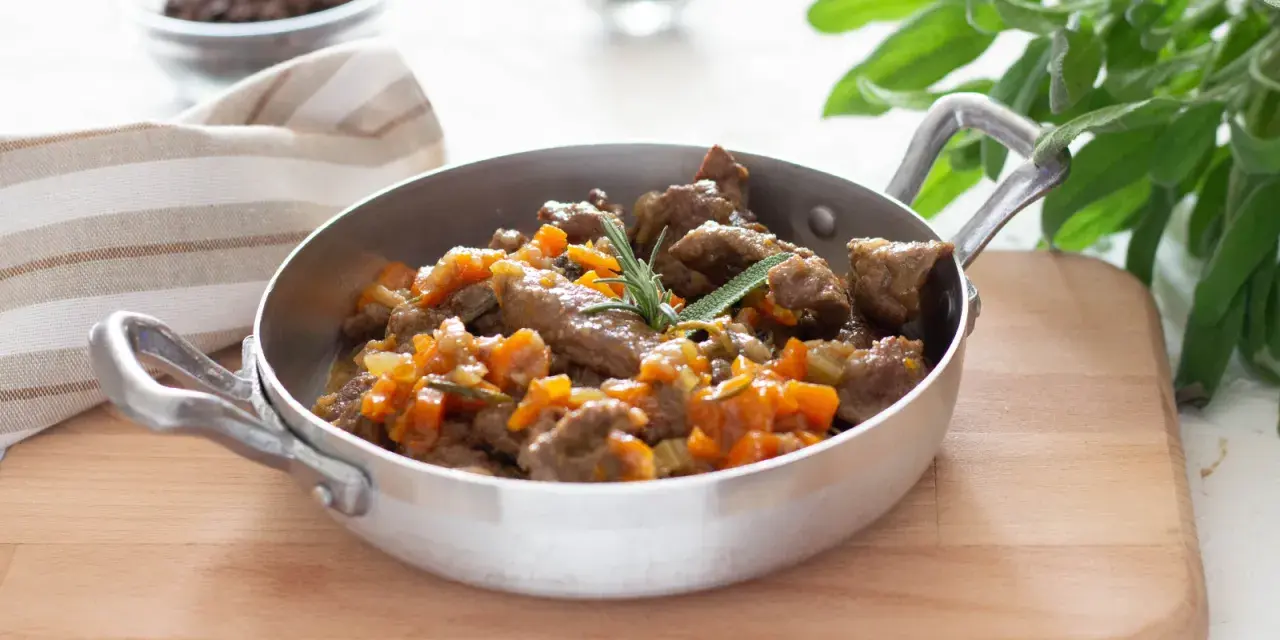 Cinghiale in umido fatto in casa da Benedetta, un piatto succulento con carne tenera e verdure, guarnito con rosmarino e salvia.