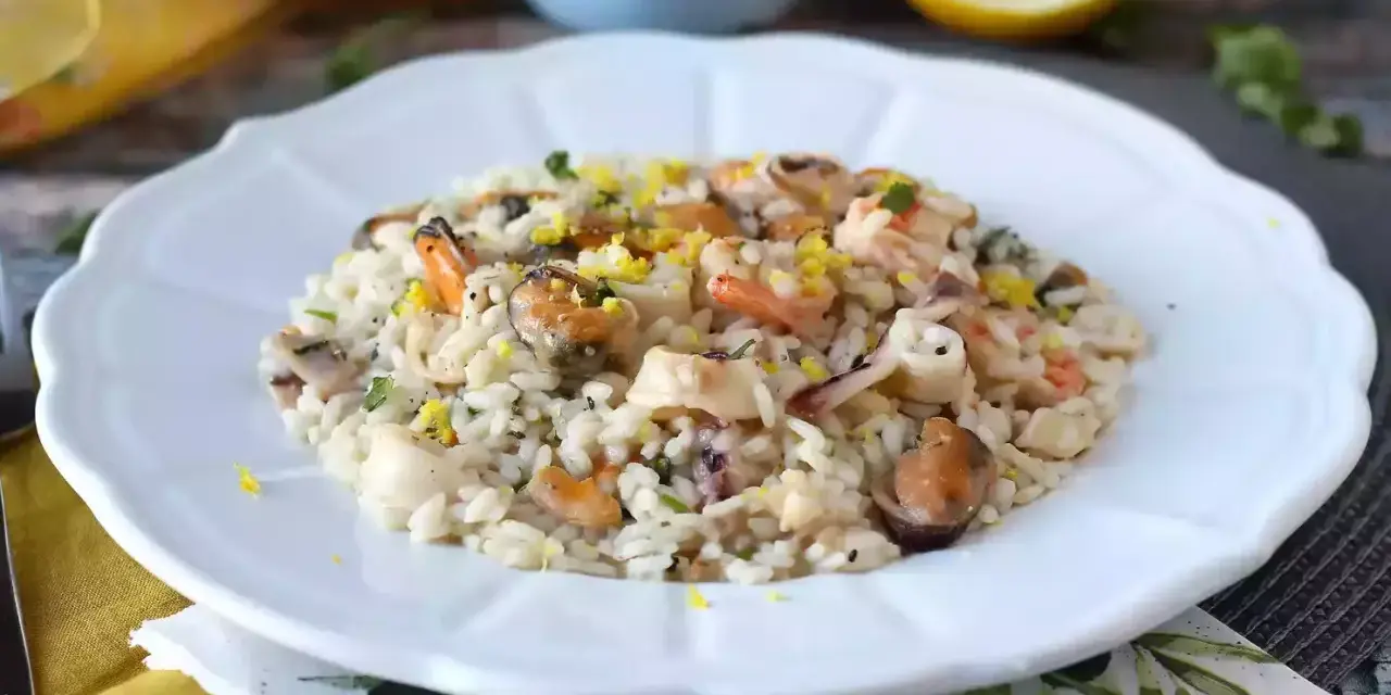 Un invitante risotto allo scoglio, ricco di cozze, gamberi e calamari, guarnito con scorza di limone.