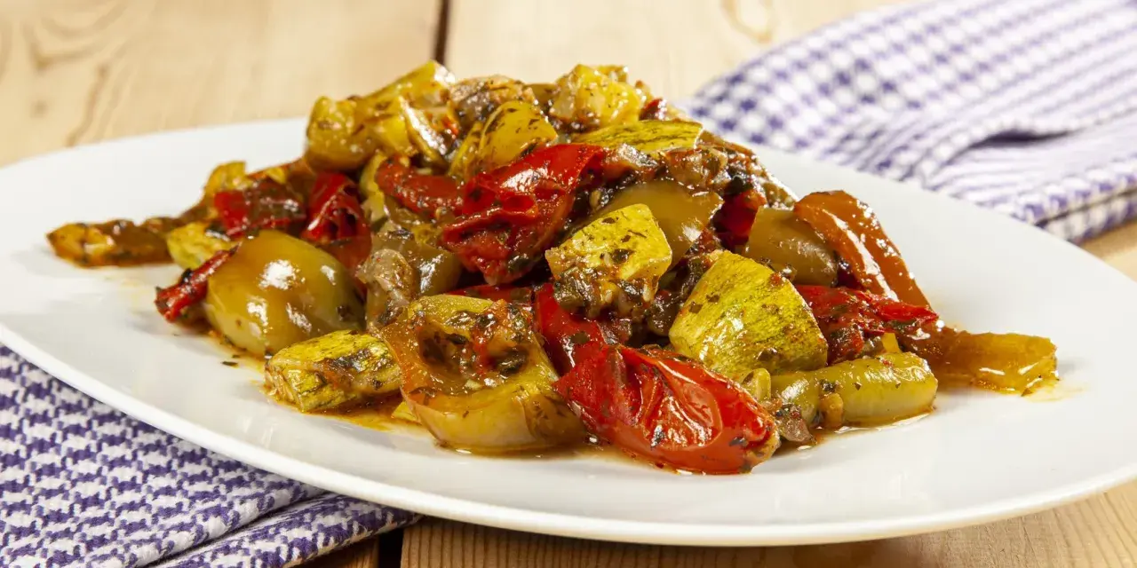Un piatto invitante di verdure miste cotte, un'ottima gurguglione ricetta, con peperoni, zucchine e pomodori conditi con erbe aromatiche.