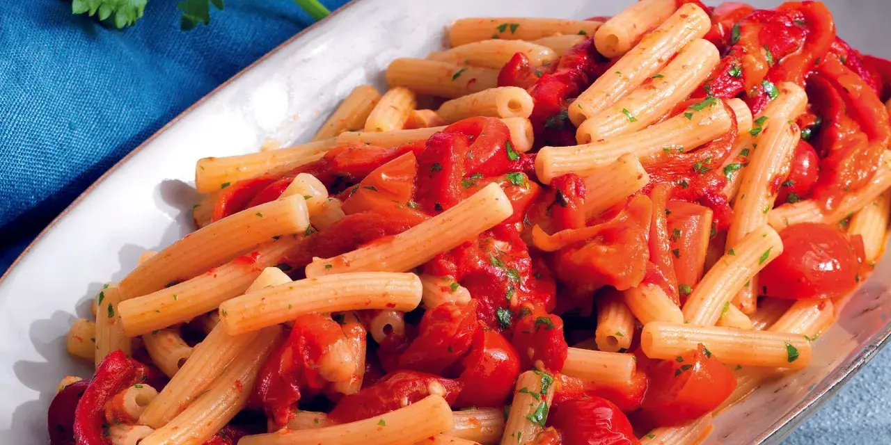 Un piatto invitante di pasta con i peperoni alla pugliese, condita con pomodoro fresco e prezzemolo.