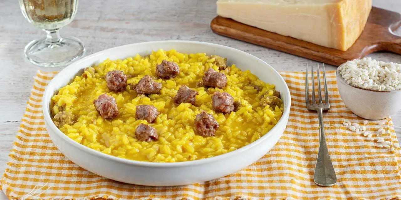 Un invitante risotto alla monzese, giallo intenso e ricco di saporiti pezzi di salsiccia, pronto per essere gustato.