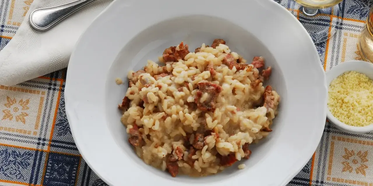 Un piatto di risotto alla pilota cremoso, con pezzetti di salsiccia, pronto per essere gustato.
