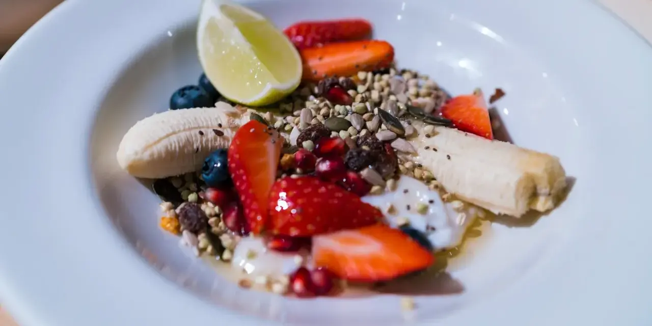 Yogurt con frutta secca, fragole, mirtilli, banana e lime. Un mix colorato e salutare per iniziare la giornata.
