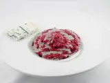 Risotto barbabietola e gorgonzola, un piatto vibrante e saporito, con una fetta di formaggio blu accanto.