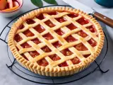 Crostata con ripieno di frutta e una griglia di pasta frolla, perfetta dimostrazione di come mettere le strisce sulla crostata.
