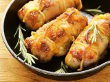 Involtini di pollo al forno dorati e succulenti, legati con spago da cucina e guarniti con rametti di rosmarino fresco, serviti in una padella di ghisa.