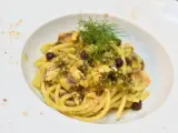 Un piatto invitante di pasta con finocchi, olive e acciughe, guarnito con erbe fresche e pangrattato.