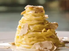Un nido di pasta al tartufo, condita con una cremosa salsa e guarnita con scaglie sottili di tartufo bianco.