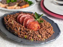Piatto di lenticchie con fette di cotechino, un classico su come si fa il cotechino. Guarnito con salvia.