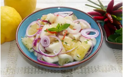 Fresca insalata di limoni, pompelmo, cipolla rossa e peperoncino, guarnita con menta.