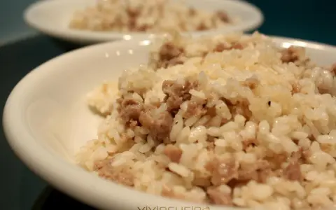 Risotto alla mantovana ingredienti: riso cremoso con salsiccia sbriciolata, servito in una ciotola bianca.