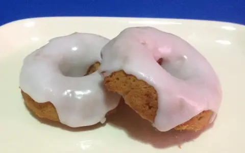 Due ciambelle con glassa di zucchero bianca e lucida, perfette per chi vuole imparare come fare la glassa di zucchero.