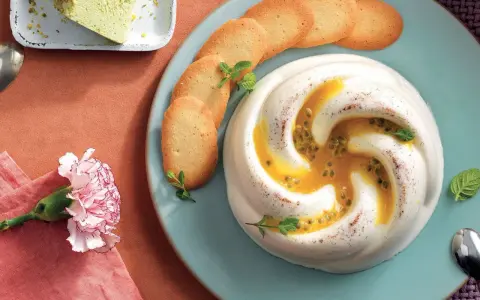 Dolce cremoso con cuore di frutto della passione, guarnito con biscotti e menta.
