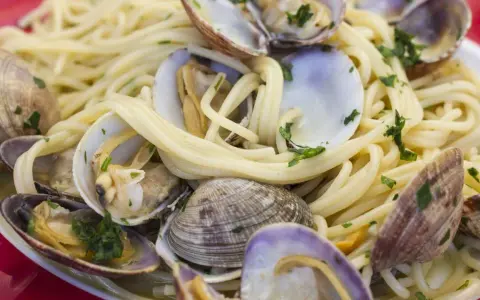 Un piatto invitante di spaghetti alle vongole, con pasta dorata e molluschi freschi guarniti da prezzemolo tritato.
