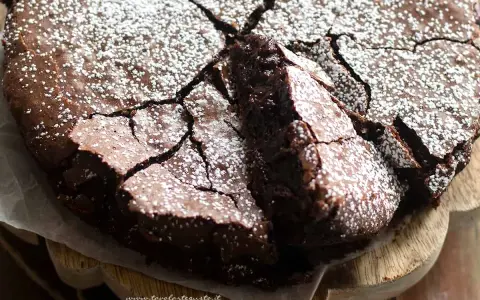 Torta fondente al cioccolato, con una crosta screpolata e cosparsa di zucchero a velo, pronta per essere gustata.