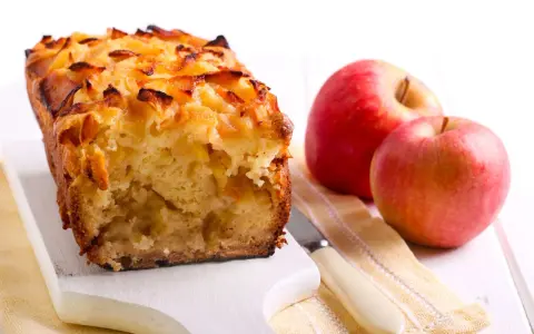 Torta con pandoro avanzato e mele, dorata e profumata, accanto a mele rosse fresche.