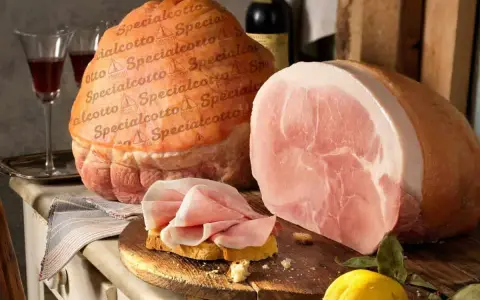 Due prosciutti, uno intero e uno affettato su pane, con una bottiglia di vino e un limone. Il cotto prosciutto è pronto per essere gustato.