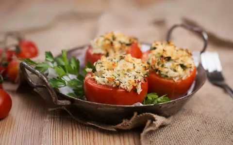 Pomodori ripieni di riso freddi, un piatto estivo gustoso e leggero, serviti in un vassoio rustico con prezzemolo fresco.