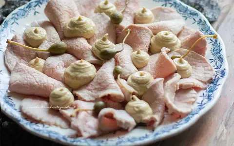 Vitello tonnato ricetta originale piemontese: fettine sottili di vitello rosa, guarnite con salsa tonnata e capperi.