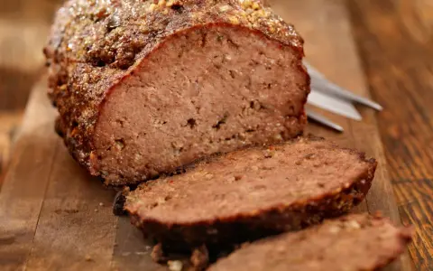 Un succulento polpettone al forno, tagliato a fette su un tagliere di legno, pronto per essere gustato.