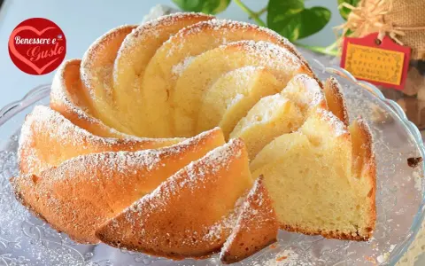 Un soffice ciambellone allo yogurt greco, spolverato di zucchero a velo, pronto per essere gustato.