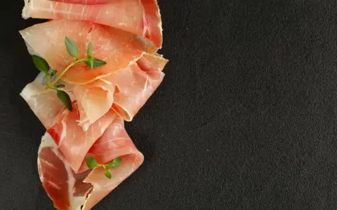 Fettine di prosciutto crudo e speck, con rametti di timo, per mostrare la differenza tra speck e prosciutto crudo.
