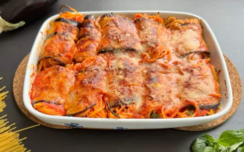 Involtini di melanzane ripieni di spaghetti al sugo, gratinati al forno con formaggio fuso.