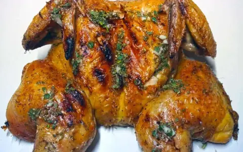 Un succulento pollo alla brace, dorato e profumato, condito con erbe aromatiche e aglio.