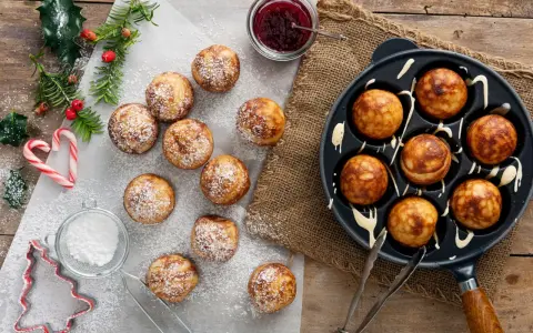 Frittelle dolci in padella, spolverate di zucchero a velo, pronte per essere gustate con marmellata.