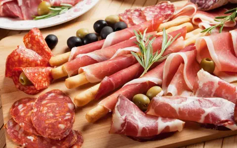 Tagliere con salumi misti, tra cui affettati non di maiale, olive e rosmarino.