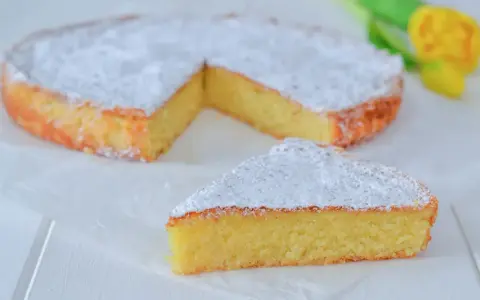 Una deliziosa torta caprese senza mandorle, spolverata di zucchero a velo, con una fetta tagliata.