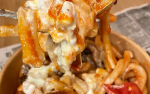 Primo piatto cremoso di pasta alla checca, con pomodoro e mozzarella filante, servito in un contenitore da asporto.