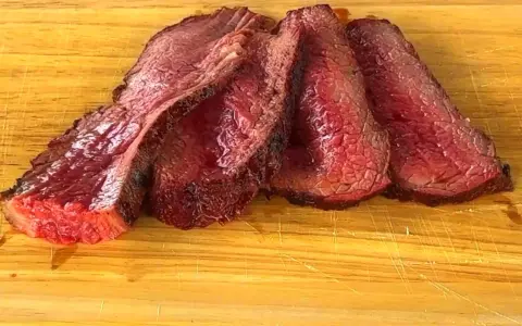 Fette succulente di spinacino di manzo, cotte alla perfezione, adagiate su un tagliere di legno.