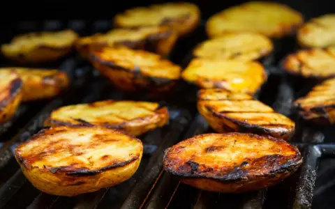 Patate alla brace dorate e succulente, con segni di grigliatura perfetti, pronte per essere gustate.