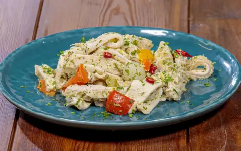 Piatto di insalata di trippa condita con erbe aromatiche, peperoncino e verdure colorate.