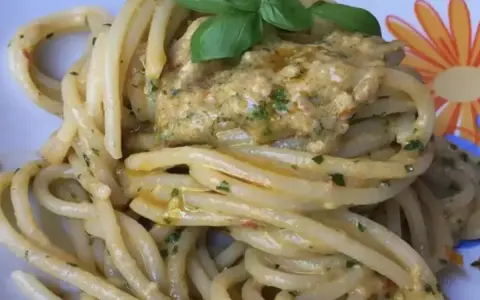 Un piatto invitante di pasta alla carlofortina, condita con un sugo cremoso e guarnita con basilico fresco.